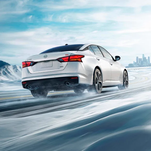 2027 Nissan Altima in white seen from behind driving in snowy landscape illustrating all-wheel drive at Orr Nissan of Shreveport in Shreveport LA